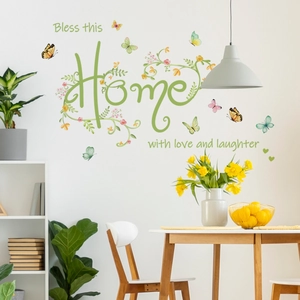 Detail view of Bless this Home wall decal with butterflies and green vine patterns