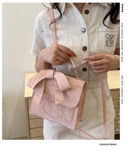 Detailed shot of pink bow handbag featuring pleated texture and silver metal hardware