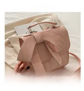 Detailed view of pink leather handbag with large bow knot and adjustable strap