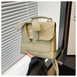 Détail du sac à main vert sauge plissé avec un grand nœud décoratif et une poignée supérieure