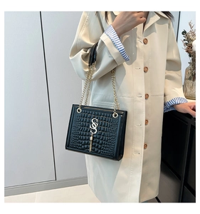 Details der schwarzen Krokodil-Tasche mit goldenem SS-Logo und Kettengurt am Modell