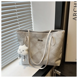 Detail of grey quilted tote bag with a cute white cloud plush pendant and slim handles