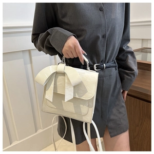 Détail du sac en cuir verni plissé blanc crème avec un grand nœud décoratif