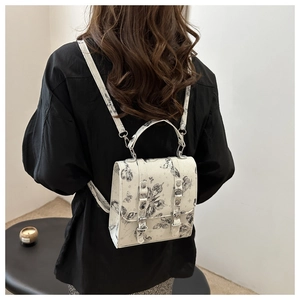 Mini backpack with black butterfly print worn by model in minimalist indoor setting