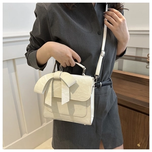 Détail du sac à main blanc crème avec nœud, texture cuir et bandoulière réglable