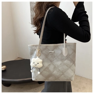 Détail du sac cabas gris matelassé avec charme nuage et logo en métal sur tissu lisse
