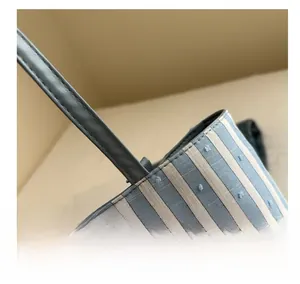 Detail of the blue striped tote bag featuring grey leather handles and fine stitching