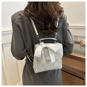 Silver grey backpack for women featuring a large bow and metallic handle on model