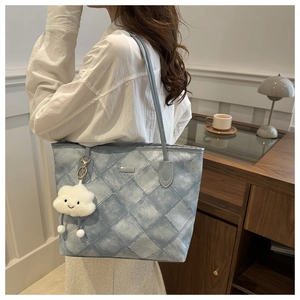 Blue tote bag with quilted pattern and plush cloud charm shown on a female model