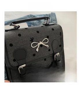 Detail of grey herringbone fabric handbag with black polka dots and silver bow decoration