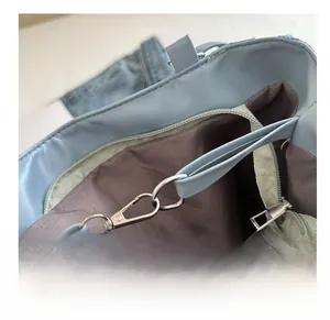 Detail shot of silver lobster clasp and leather strap on light blue plaid tote bag