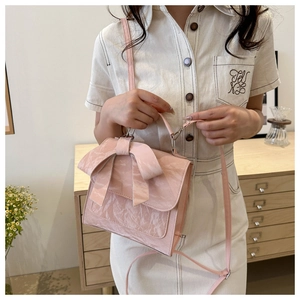 Détail du sac à main rose clair avec un grand nœud décoratif et une boucle dorée