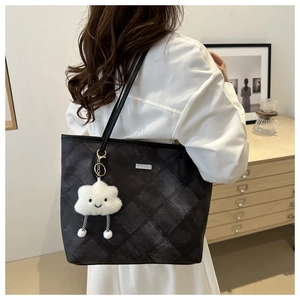 Detail of dark grey quilted tote bag with cute plush cloud charm on a shoulder strap