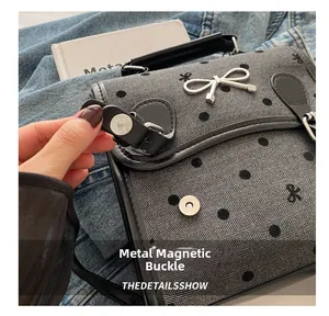 Close-up of grey polka dot bag featuring a silver metal bow and magnetic snap closure