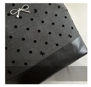 Macro shot of gray herringbone fabric with black polka dots and silver bow charm detail