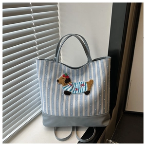 Detail of blue striped canvas tote with embroidered dog patch and leather bottom trim