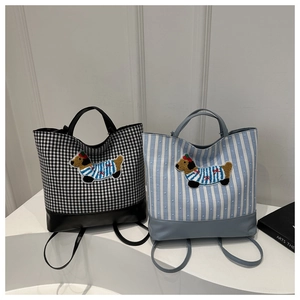 Detail view of plaid and striped canvas bags with leather trim and cartoon dog patches