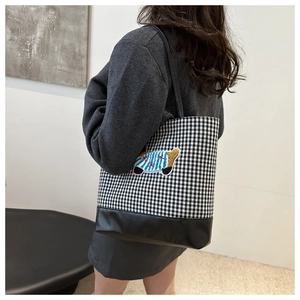 Detail of checkered tote bag featuring a cute cartoon bear embroidery and leather base