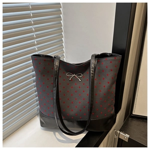 Close-up of fabric tote with red heart embroidery and silver metal bow detail