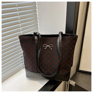 Detail of black tote bag with red heart patterns and silver metal bow decoration