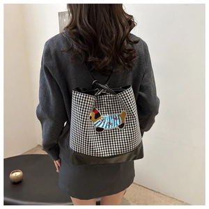 Detail of checkered canvas backpack with cartoon puppy embroidery and leather trim