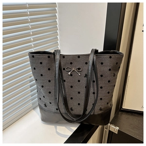 Detailed view of canvas tote bag featuring polka dot pattern and metal bow accent