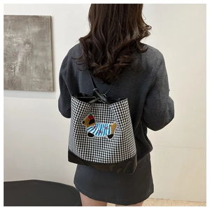 Detail of checkered tote bag featuring cartoon dog embroidery and durable black base