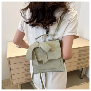 Detailed shot of light green bow backpack with pleated texture on a model shoulder