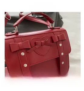 Detail view of red heart-shaped stitching and bows on a vegan leather crossbody bag