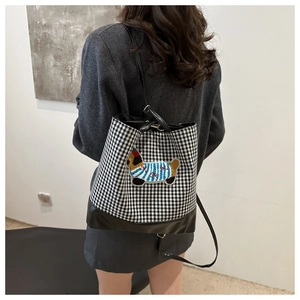 Detailed back view of a plaid gingham tote bag with cartoon dog patch on a model