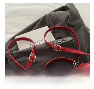 Detail of red PU leather bag with adjustable slim strap, silver buckle, and bow ornament