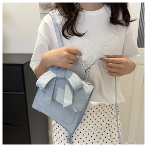 Detail of light blue bow handbag with pleated leather texture and adjustable shoulder strap