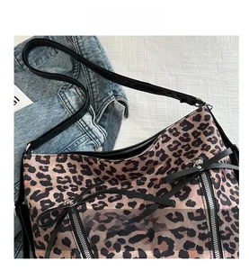 Primer plano del bolso tote de leopardo con cremalleras plateadas y correa de cuero negro