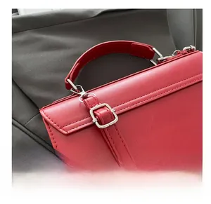 Detail of red leather messenger bag featuring silver metal swivel hooks and buckle
