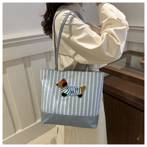 Detail showing blue and white striped tote bag with cute cartoon dog embroidery