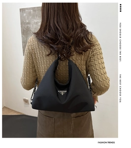 Black nylon hobo bag featuring a metal triangle logo and mixed chain strap on a model