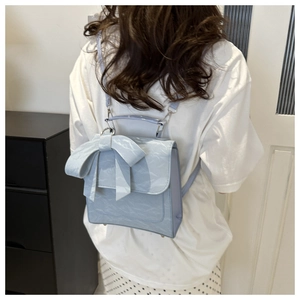 Vue détaillée du sac bleu clair à texture marbrée avec nœud porté par un modèle