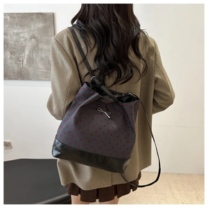 Detailed view of grey polka dot bucket bag with bow pendant and black leather base