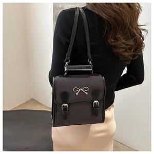 Detail of grey fabric handbag with red heart print and silver bow buckle on model