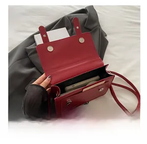 Detail of red matte leather crossbody bag with silver buckle and magnetic closure