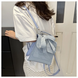 Detail of light blue bow backpack featuring pleated texture and soft PU leather material