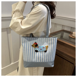 Detail of blue striped tote bag with cute dog embroidery on female model side profile