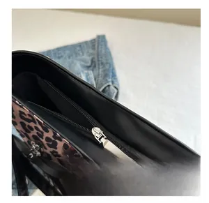 Primer plano del bolso tote de leopardo con cremallera negra y herrajes de metal