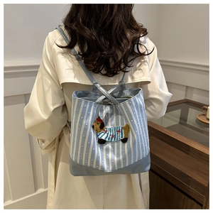 Detailed embroidery of a dog motif on a blue and white striped tote bag