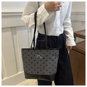 Detail of grey canvas tote bag with black polka dots and silver bow charm on leather base