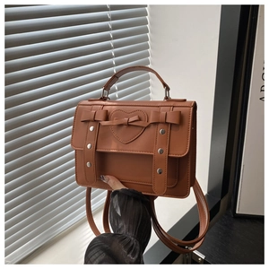 Detailed close-up of brown vintage PU leather bag with heart emboss and bow decoration