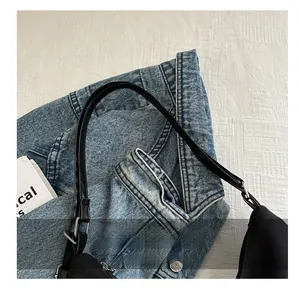 Detail of black nylon tote with leather handle and silver metal buckle on a denim jacket