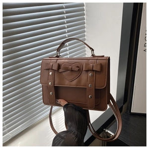 Detailed view of the brown school style handbag with bowknot and heart accents