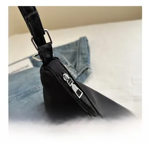Detail of a black minimalist bag showing smooth silver zipper and waterproof fabric