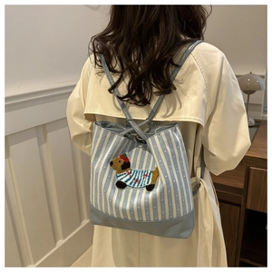 Detail of blue striped canvas backpack with cute puppy embroidery and leather base on a model